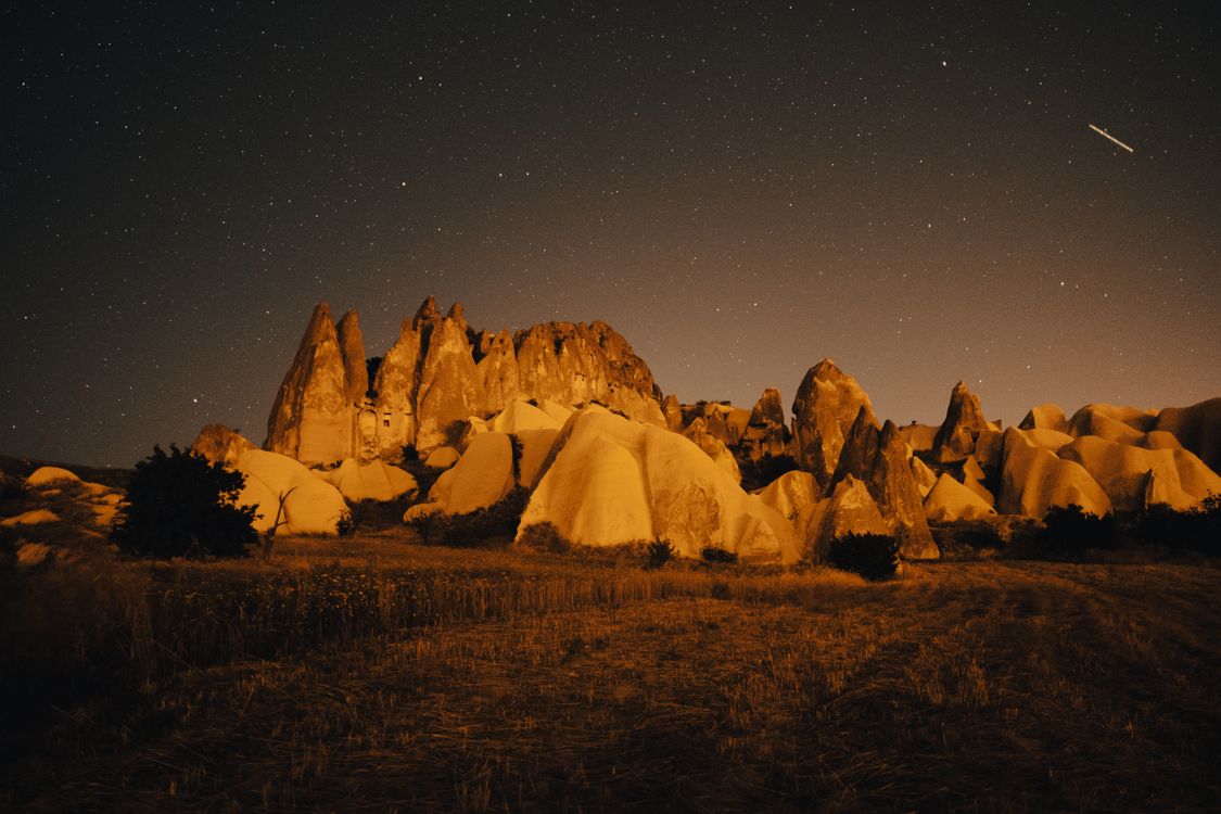 A Rock Formations Near the Grass Field Under the Starry Sky at Night ...