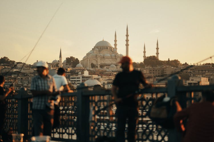 People Standing On The Bridge While Holding Fishing Rods