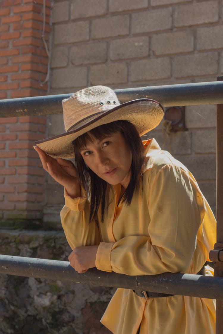 Woman In Cowboy Hat Leaning On Metal Railing