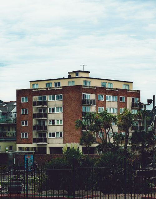 Free A modern apartment building surrounded by palm trees, showcasing architectural design. Stock Photo