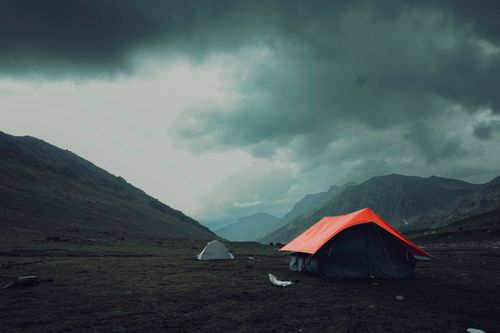 Free A dramatic scene of camping tents set against the stunning mountains in Kashmir, India, under looming storm clouds. Stock Photo