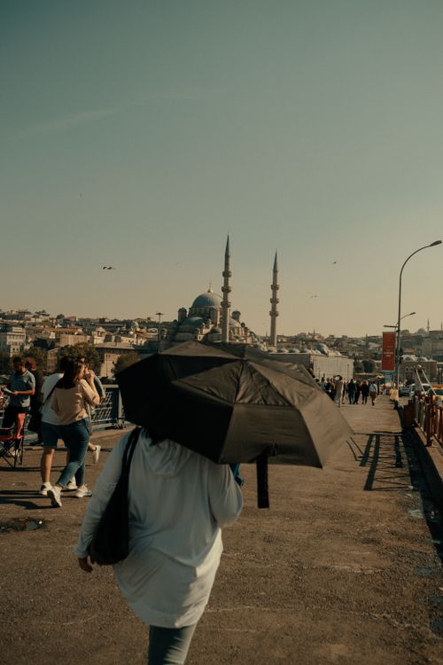 Free A woman with an umbrella walks on a bridge in Istanbul, capturing a classic cityscape. Stock Photo