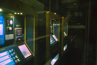 Row of illuminated ticket machines in a dark setting with a reflective perspective.