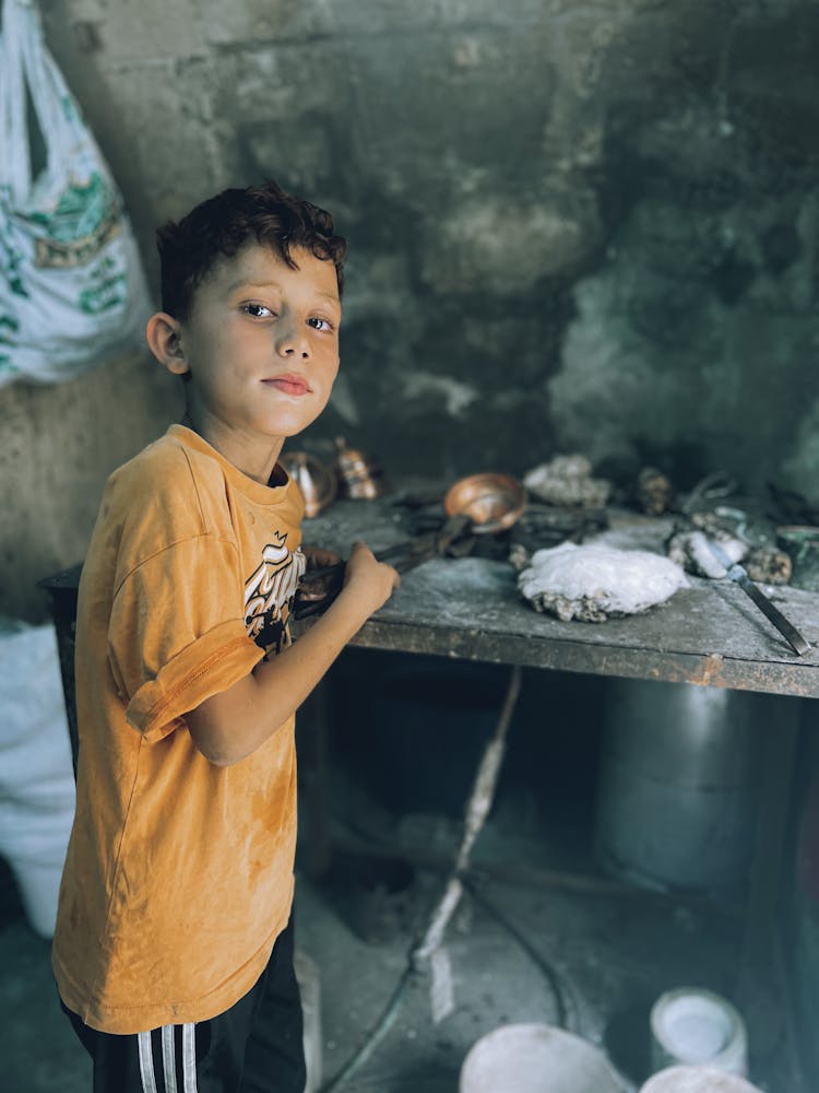 A Boy Standing In A Workshop 