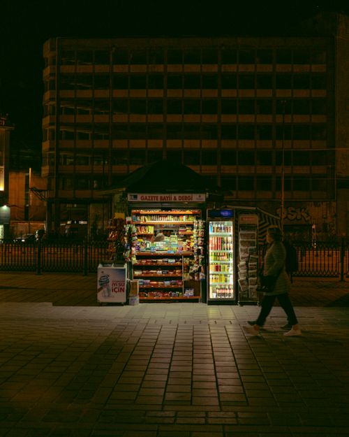 Free A bustling urban street scene featuring a brightly lit kiosk at night, capturing the essence of city life. Stock Photo