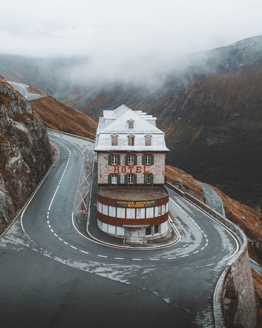 A unique hotel situated on a winding mountain road amidst dense fog, creating a mysterious atmosphere.