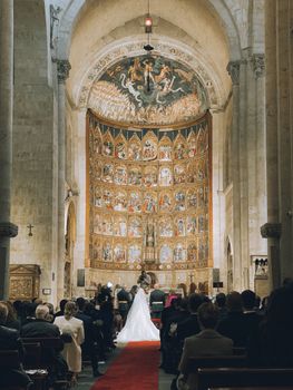 A wedding ceremony inside a grand cathedral with ornate decorations and guests in attendance.
