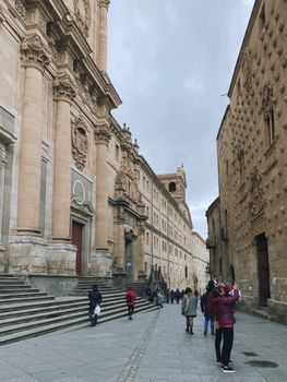 Tourists walking by a historic cathedral facade in an urban setting.