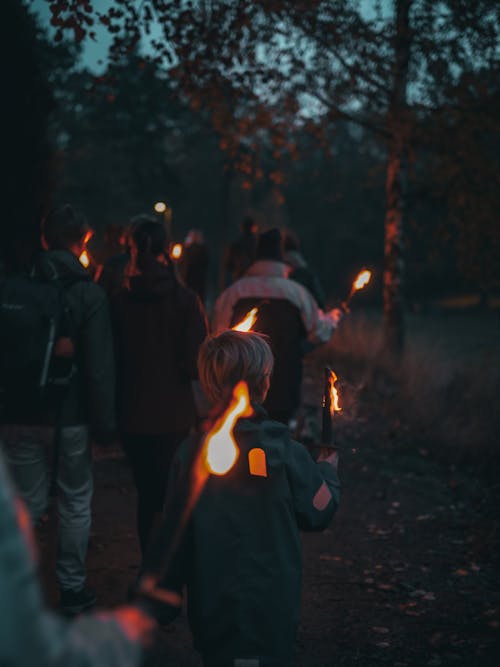 People Walking with Torches in Forest