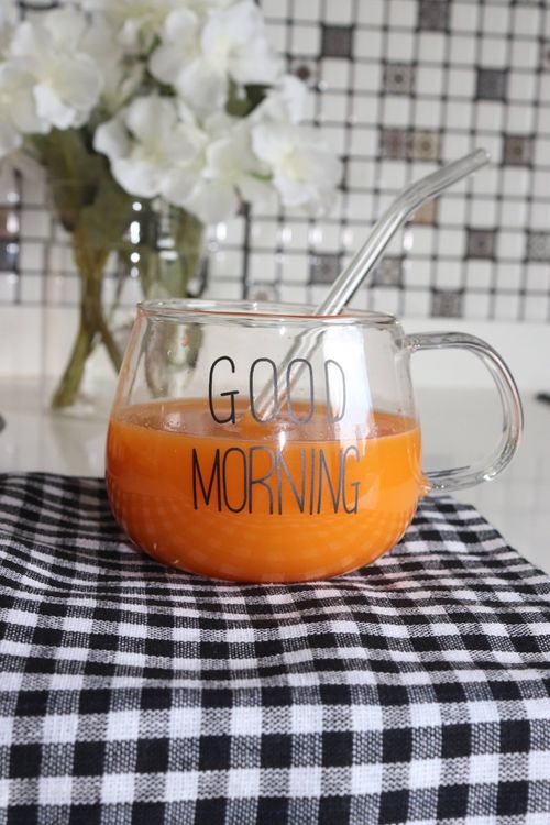 Free Glass cup filled with orange juice featuring 'Good Morning' text on checkered cloth. Stock Photo