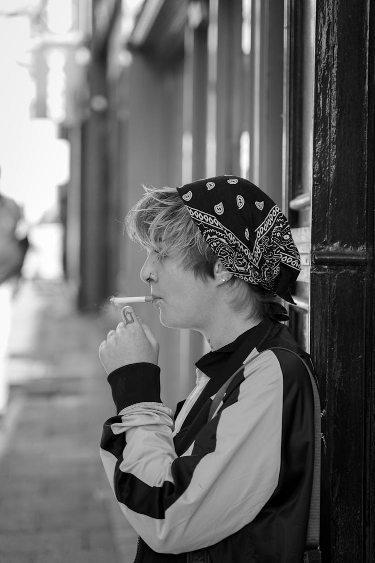 Young Man Smoking A Cigarette On A Sidewalk 