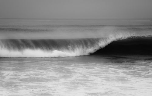 Free Captivating black and white photo of a powerful ocean wave crashing onto the shore. Stock Photo