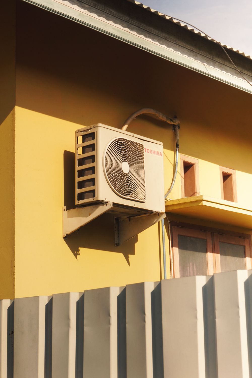 Outdoor air conditioner condenser unit mounted on a wall