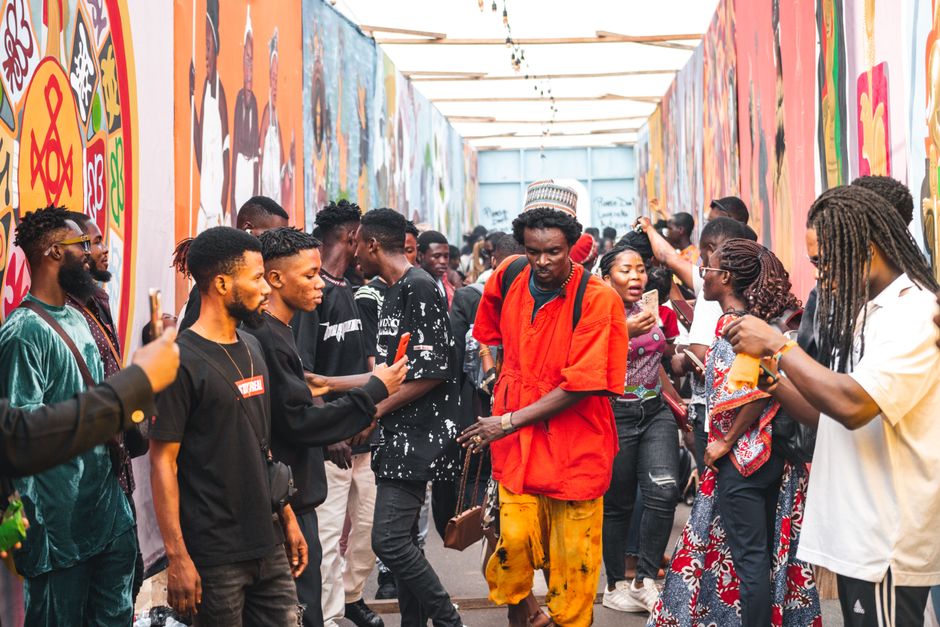 Dynamic crowd at an Accra festival, showcasing colorful murals and lively interactions.