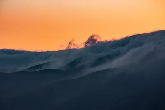 A stunning sunset in Guadalupe, Mexico, with clouds enveloping the hills, creating a serene atmosphere.