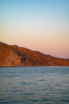 Scenic sunset view of a Turkish coastline with calm waters and mountainous backdrop.