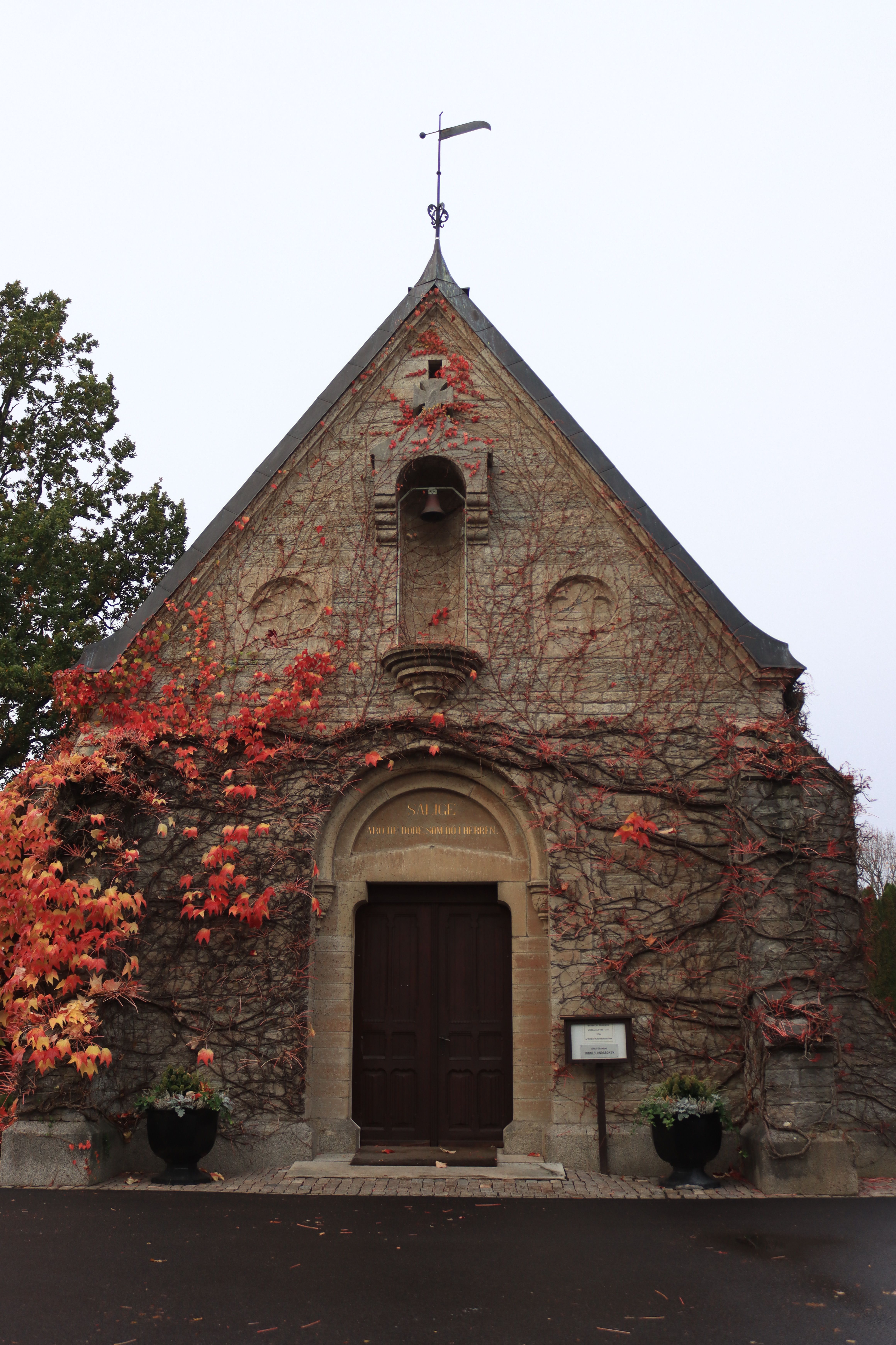 Charming stone church in Jönköping, Sweden, with vibrant autumn ivy covering the facade.