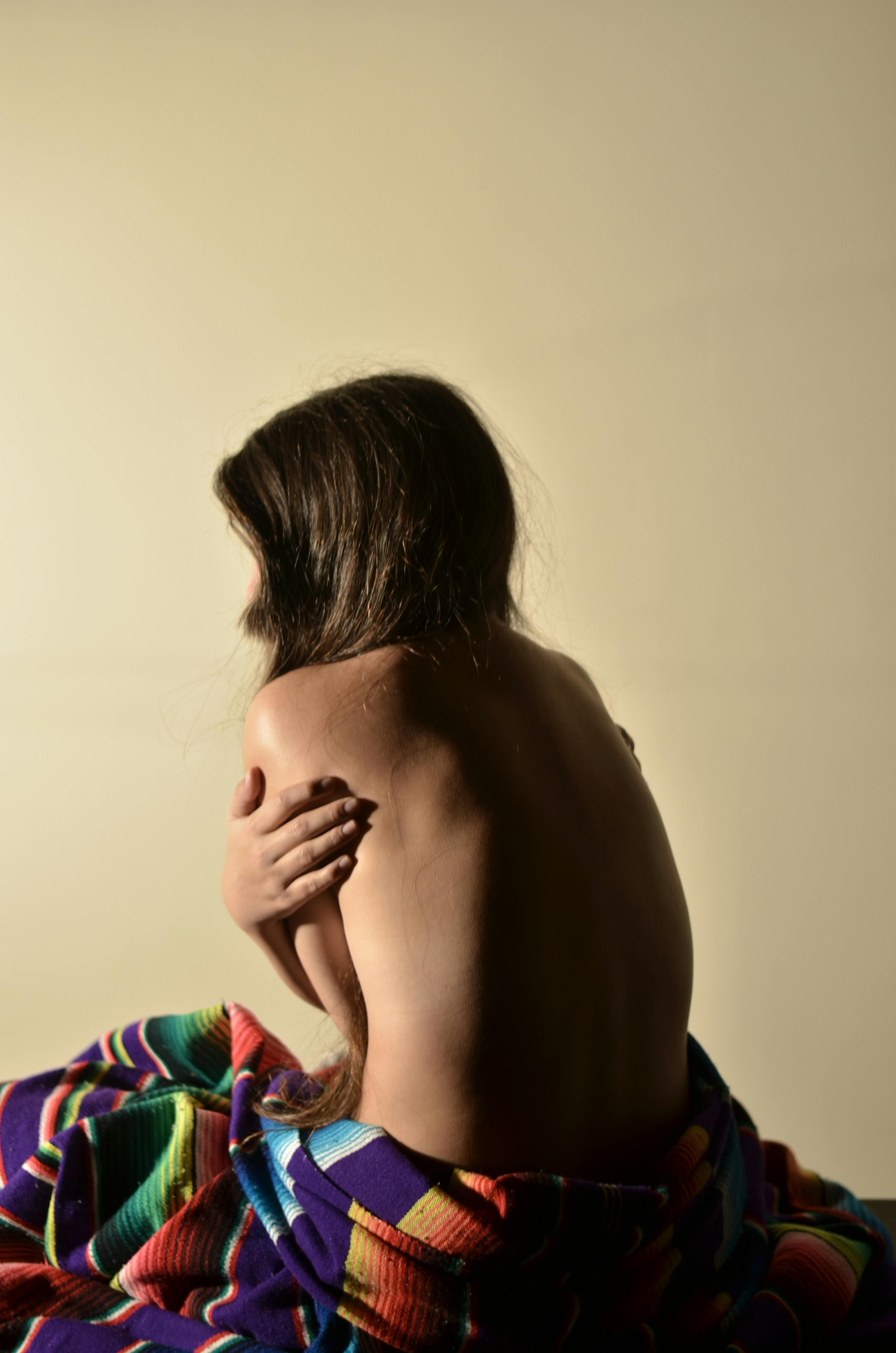 topless woman hugging herself inside yellow painted room