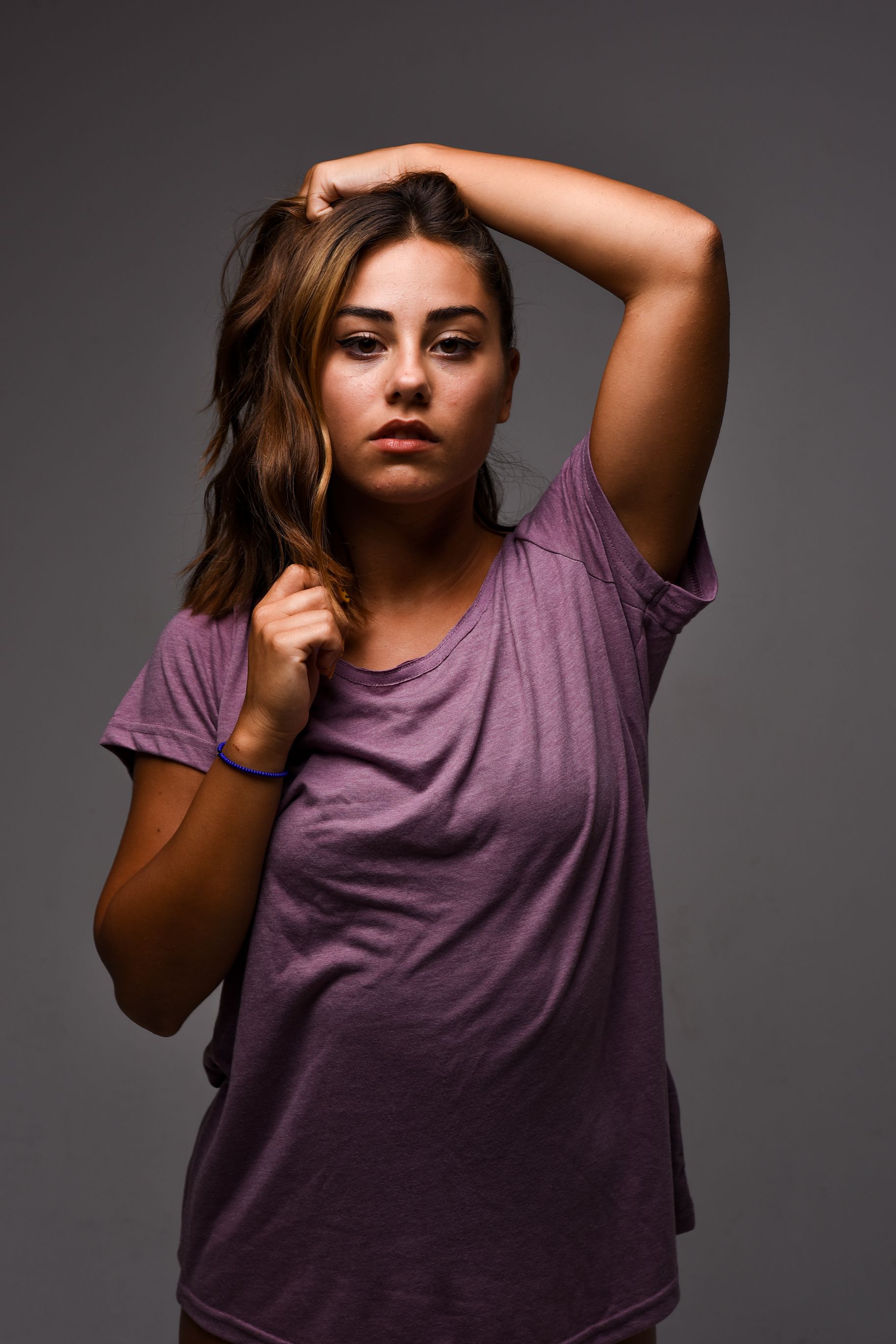 Elegant portrait of a woman posing confidently against a gray backdrop.