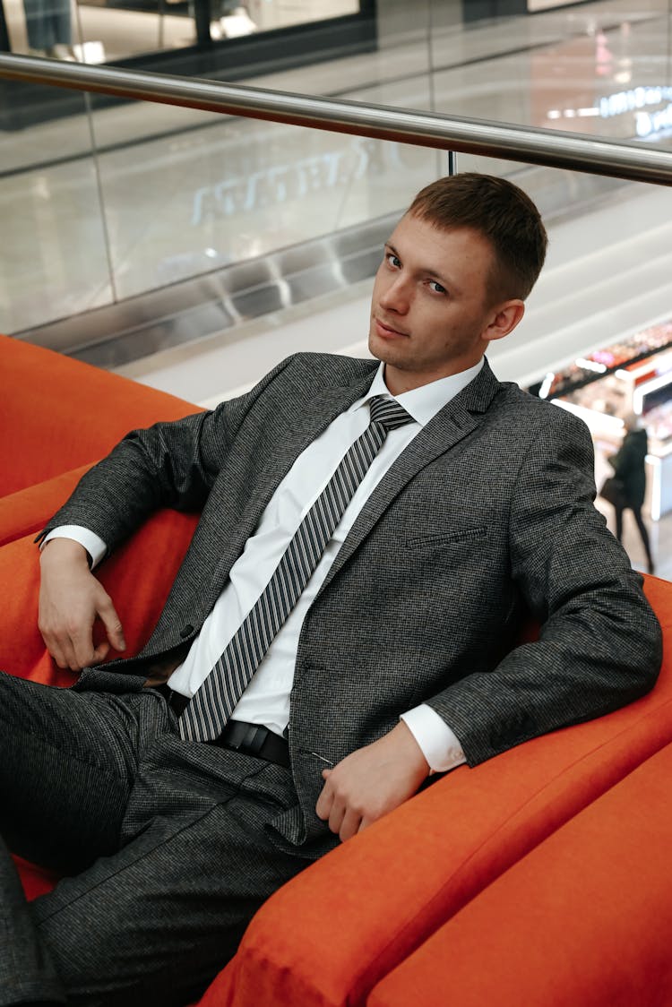 A Man In A Suit Sitting On A Chair 