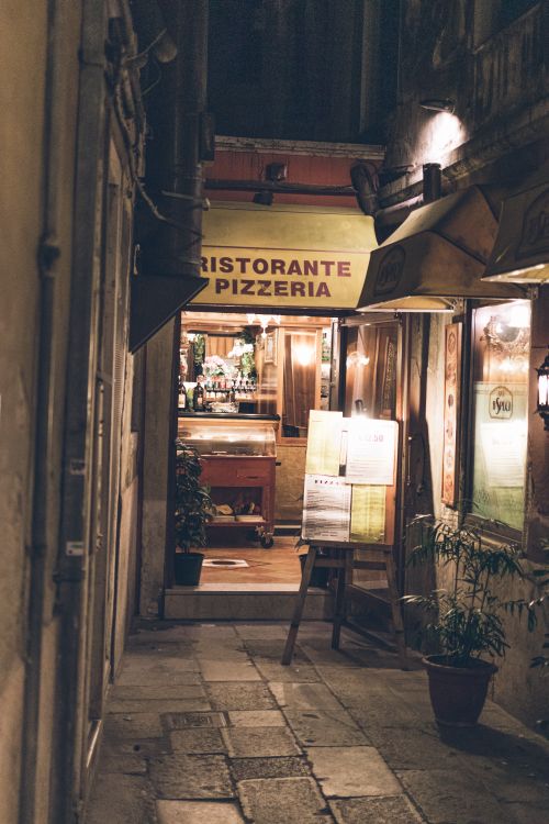 Free Dimly lit alleyway leading to a charming Italian restaurant with warm inviting lights. Stock Photo