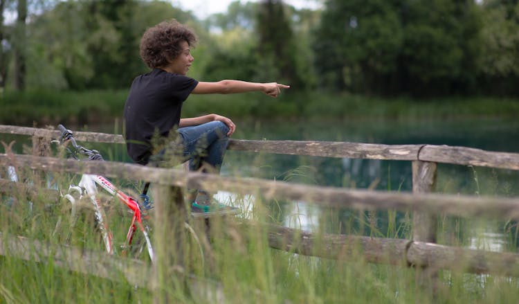 Young Boy Sitting On A Bike Near Water 