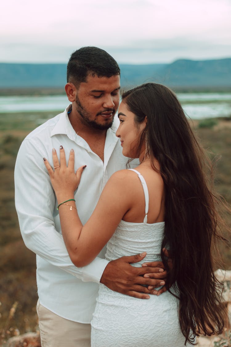 Engaged Couple Dressed In White Embracing