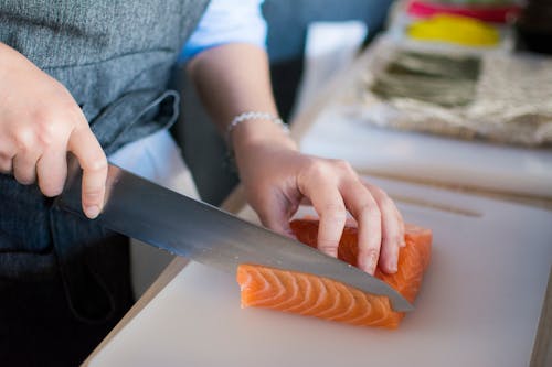 Free Person Slicing Meat On White Chopping Board Stock Photo