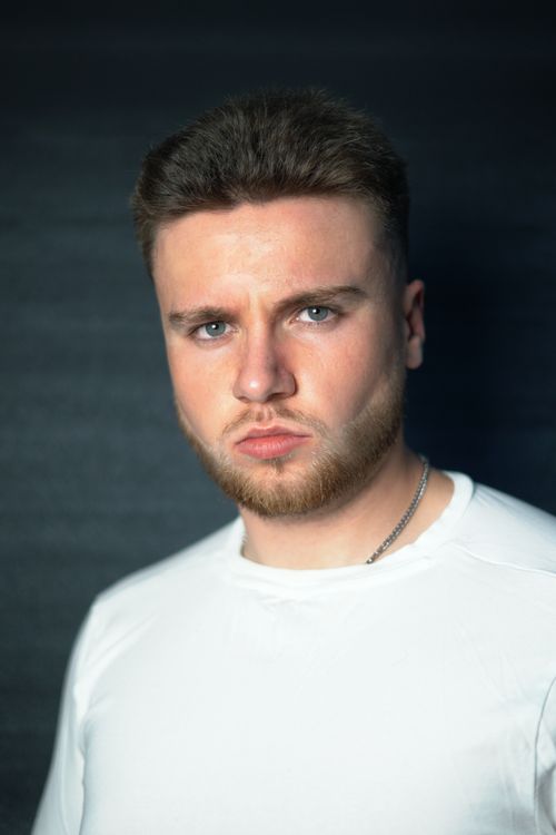 Free Close-up portrait of a young man with a beard and serious expression wearing a white shirt. Stock Photo