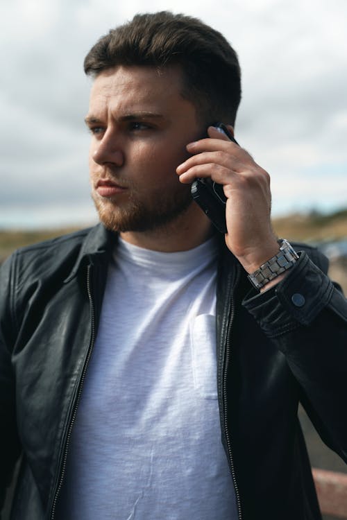 A Man in Black Leather Jacket Talking on the Phone