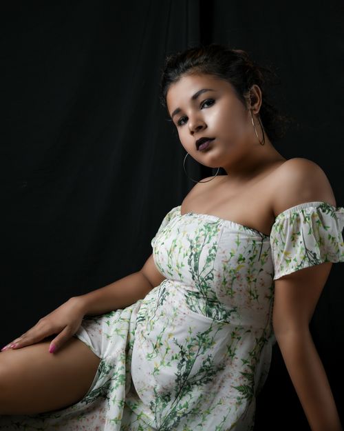 Free Stylish portrait of a woman in a floral dress against a black backdrop, exuding elegance. Stock Photo