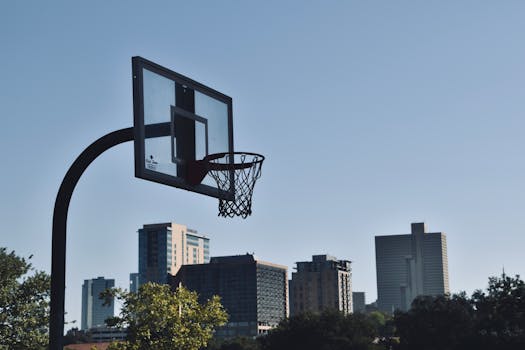 A basketball hoop stands tall with a vibrant urban skyline in the background, evoking the spirit of city sports.