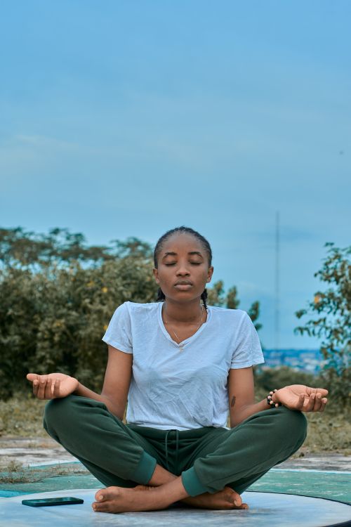 Free Woman meditating outdoors in green pants and white shirt, embracing wellness and tranquility. Stock Photo