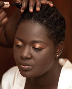 A young woman getting a makeup session in Mampon, Ghana. Close-up view.