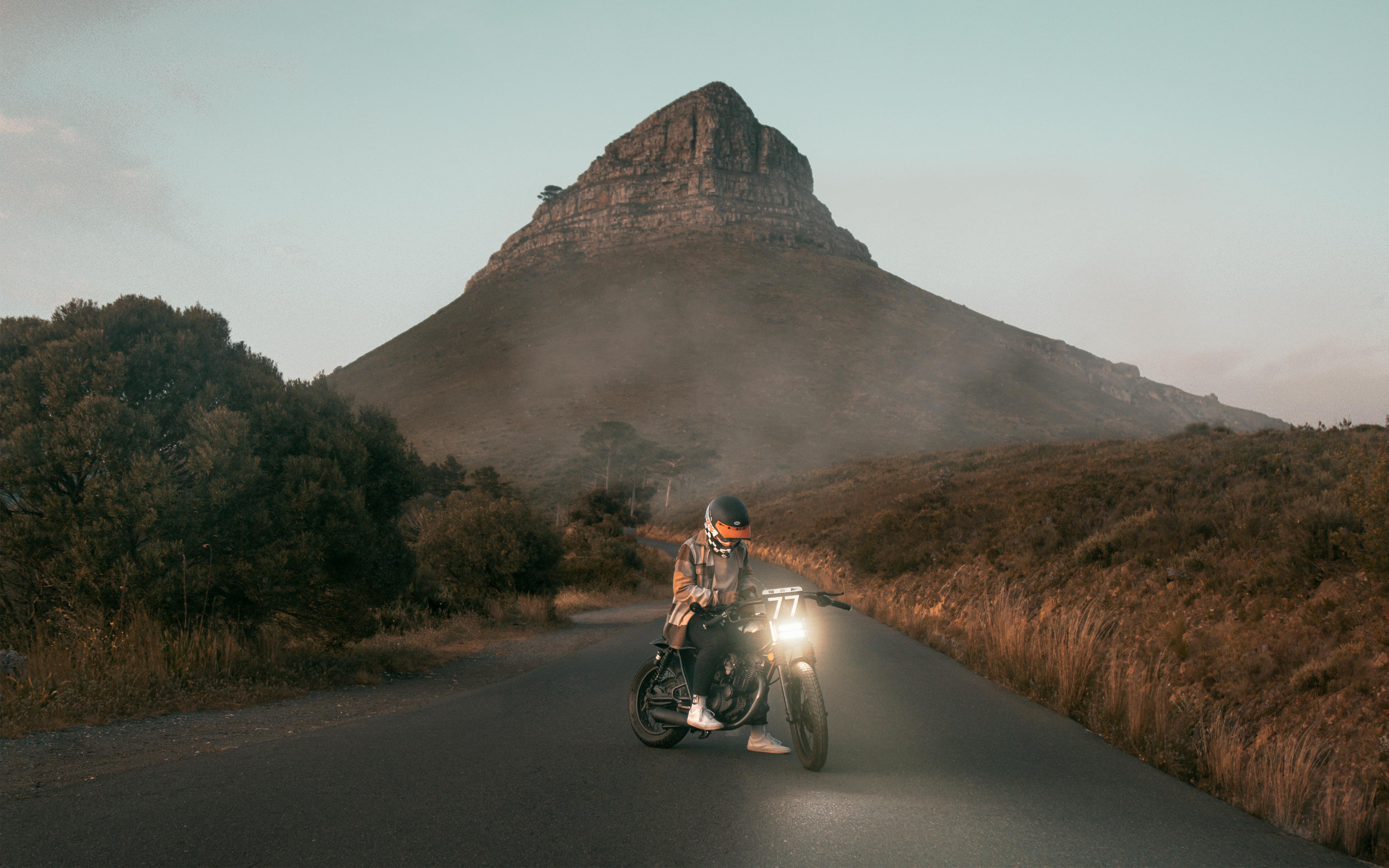 A motorcyclist rides down a road near Lions Head, Cape Town, during a stunning sunrise.