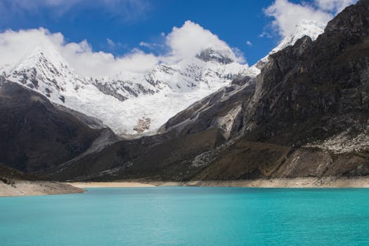 Stunning turquoise lake surrounded by majestic snow-covered mountains under a blue sky.