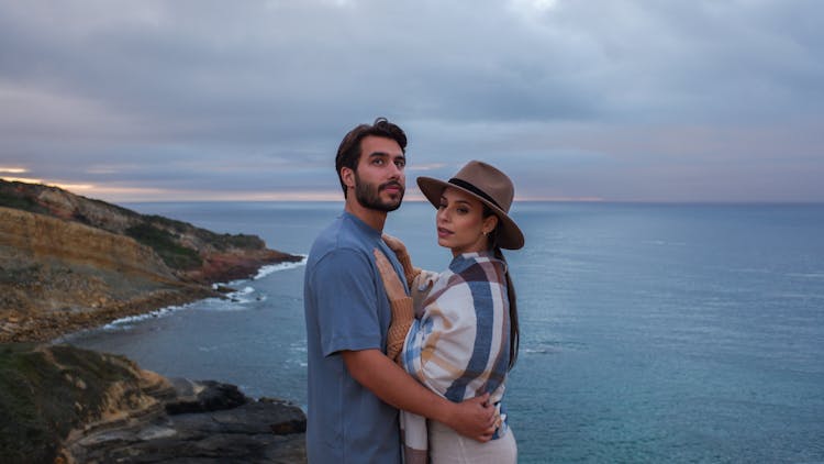 A Couple On Top Of A Mountain Near The Sea