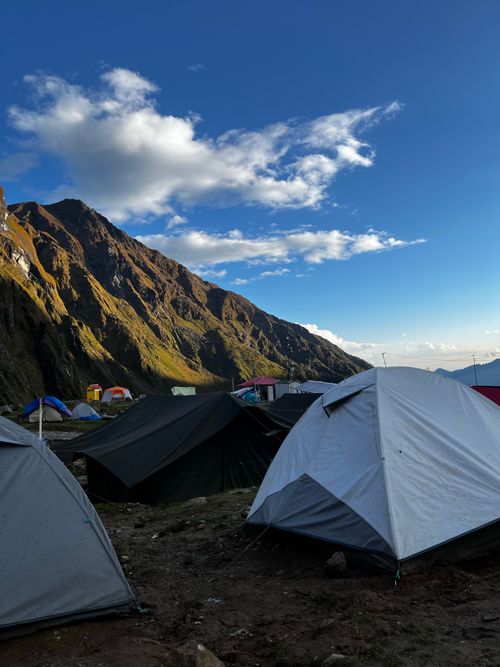 Free A picturesque campsite with tents set against a stunning mountain backdrop under a clear blue sky. Stock Photo