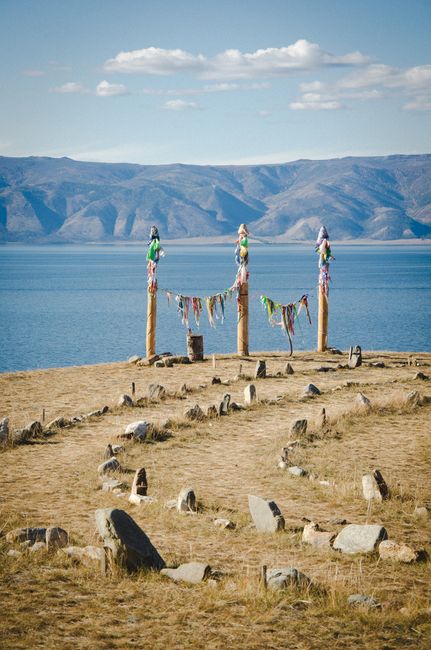 Colorful ribbons adorn ritual posts by a serene mountain lake.