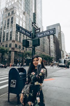 A fashionable woman poses on Fifth Avenue, NYC with city skyscrapers in the background.