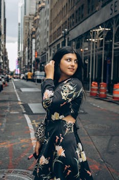 Stylish woman in a floral dress poses confidently on a bustling New York City street.
