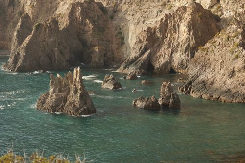 Free Breathtaking view of rugged coastal rock formations merging into the turquoise sea under daylight. Stock Photo