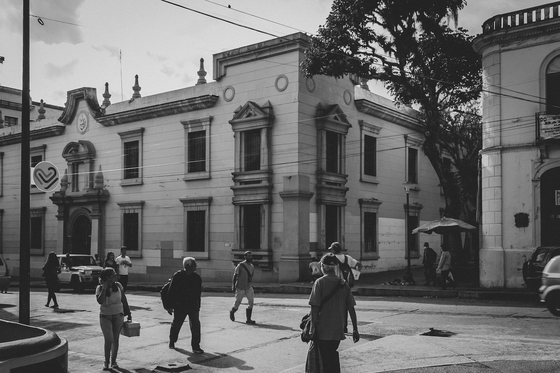 Black and white street scene in Mérida, Venezuela showing pedestrians and historic architecture.