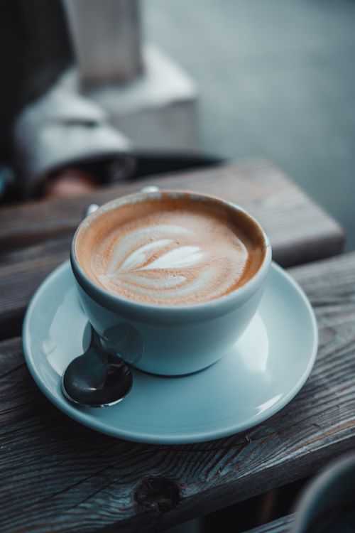 Free A steaming cup of beautifully crafted latte art placed on a rustic wooden table in Vienna. Stock Photo