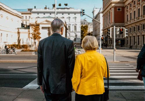 Free Back view of an elderly couple standing at a zebra crossing in a city. Stock Photo