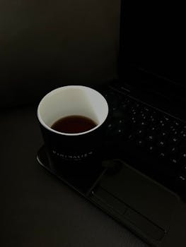 Simple black coffee cup beside a sleek laptop, embodying a minimalist workspace.