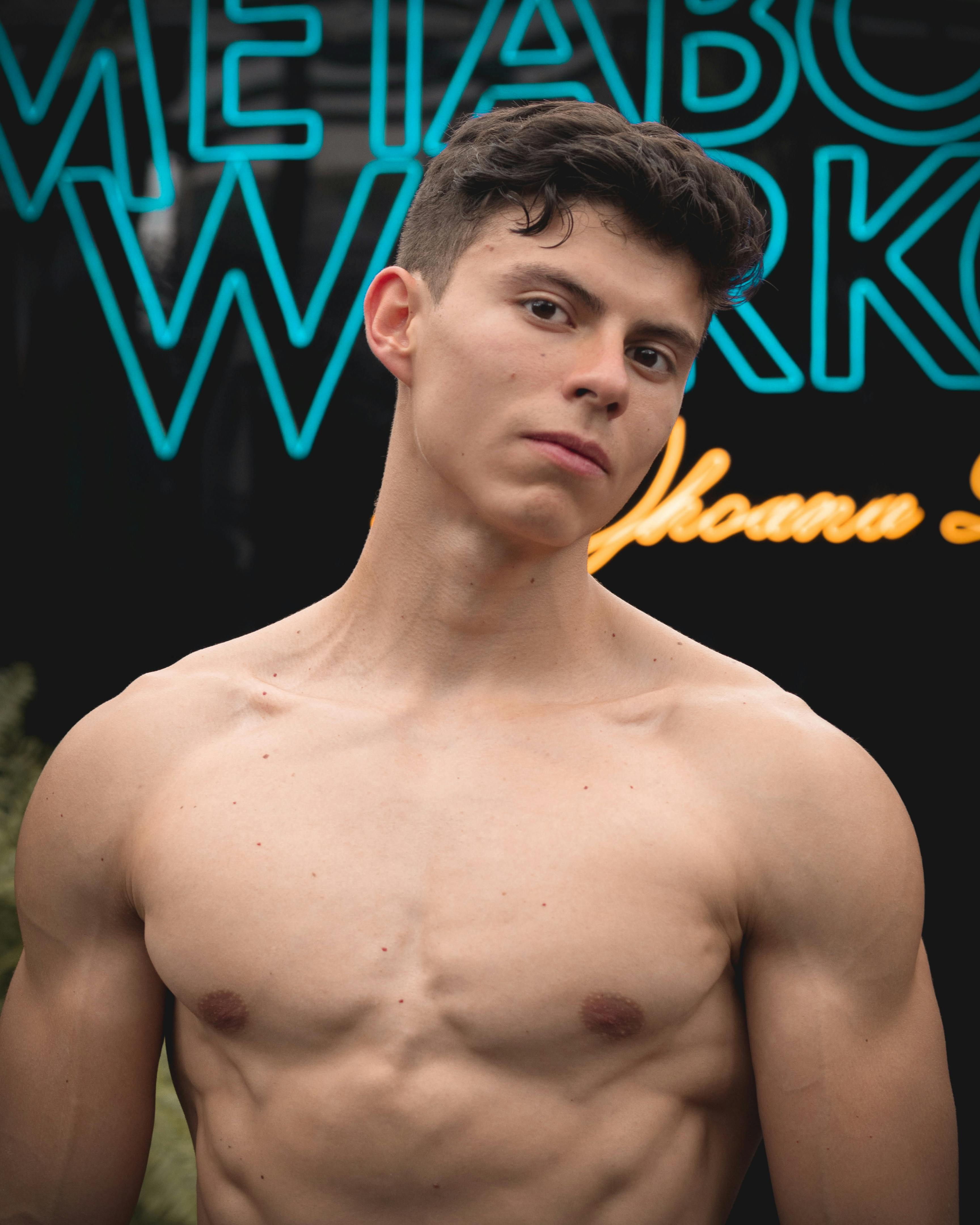 Muscular young man posing shirtless outdoors, fitness lifestyle.