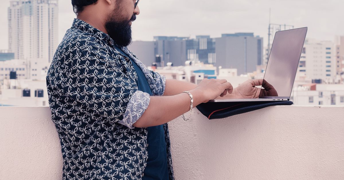 Man Standing Computer Man Standing Beside White Wall Holding Laptop Computer · Free Stock Photo