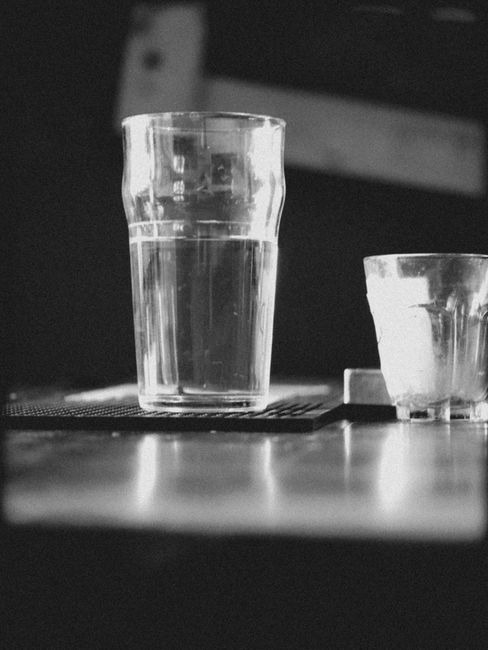 Black and white photo of a pint and shot glass on a wooden table.