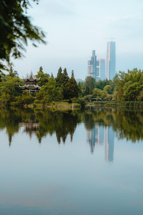 Free Peaceful urban park featuring skyline reflection and lush greenery. Stock Photo